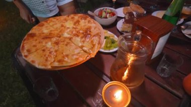 Lezzetli Imereti Khachapuri yemekte arkadaşlar arasında masada. Onlar birlikte akşam yemeği yiyecekler. Gürcistan mutfağında Gürcistan ziyafeti.