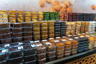 Çeşitli kurutulmuş meyve ve fıstıklarla dolu plastik kaplar metal bir rafta, müşterilerin onları toplamasını bekliyor.