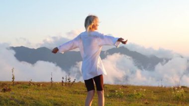 Kadın, kollarını açarak çimenli bir dağın tepesinde duruyor. Etrafını saran bulutların ve dağların güzelliğini kucaklıyor. Dans eder ve hayattan gülümseyerek zevk alır. Yavaş çekim
