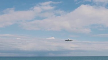 Beyaz çift motorlu yolcu uçağı havaalanına yaklaşıyor. İniş takımlarını denizin üzerine indiriyor ve genişletiyor, Gürcistan Batumi.