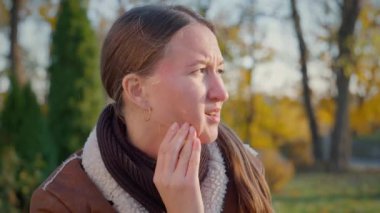 Parktaki bankta oturan kadın şiddetli diş ağrısından muzdarip. Soğuk sonbahar havasında diş hastalığıyla boğuşurken ifadesi stresi ortaya çıkarıyor.