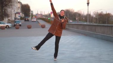 Kadın akıllı telefonuyla aldığı güzel haberi kutlarken neşe dolu dans şehir köprüsünü dolduruyor. Neşe onun tasasız hareketlerinden yayılıyor, mutluluk ve heyecanı somutlaştırıyor.