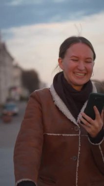 Kadın akıllı telefonuyla aldığı güzel haberi kutlarken neşe dolu dans şehir köprüsünü dolduruyor. Mutluluk ve heyecanı somutlaştıran gamsız hareketlerinden neşe yayılıyor. dikey video