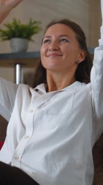 İş kadını ofisinde rahatça oturuyor, elleri başının arkasında dinleniyor. Rahatlama anının tadını çıkarırken, iş ortamında sükunet ve tatmin duygusunu somutlaştırıyor. dikey video