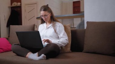 Genç bir kadın dizüstü bilgisayar ekranında kaşlarını çatarken gözlüklerini ayarlıyor. Uzaktaki işlerle uğraşırken yüzünün allak bullak olması ve hayal kırıklığı yansıyor.