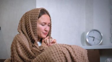 Örülmüş battaniyeye sarılmış bir kadın soğuktan titreyerek, borç yüzünden merkezi ısıtma sistemi olmayan bir dairede tek başına oturur. İçerde ısınmaya çalışınca rahatsız oluyor.