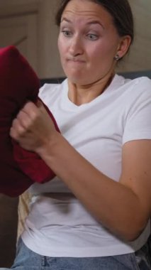 Kanepede oturan genç bir kadın karnını tutuyor. Karın ağrısı çektiği çok açık. Sindirim sorunlarıyla uğraşırken yüzünde rahatsızlık yayılıyor. dikey video