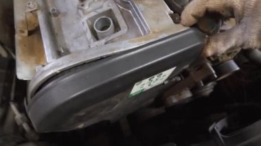 Tamircinin elleri plastik kapağı kaldırır, zamanlayıcı, gerilim ve bakım sırasında araba motorunun çeşitli bileşenlerini ortaya çıkarır.