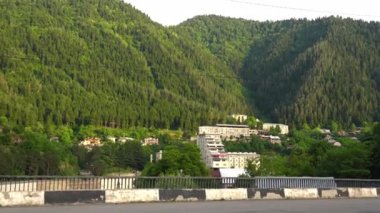 Bakuriani kasabasını çevreleyen yeşil dağ manzarası, bereketli ormanları ve parlak güneş ışığı altında sakin yeşil yamaçları olan manzaralı kafkas arazisini gözler önüne seriyor.