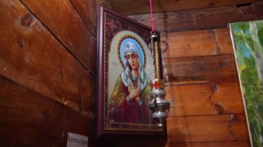Bakire Meryem 'in dini simgesi, yumuşacık ahşap duvara asılıyor, yumuşak ortam ışığı huzur dolu kilisenin içinde kutsal mekanı aydınlatıyor, ruhsal saygıyı somutlaştırıyor.