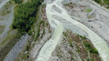 Turkuaz buzul nehri kayalık vadiden akıyor. Kurtarma ekibi ve araçlar yakınlarda park halinde. Bu da insansız hava aracı ihtimalini gösteriyor..