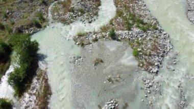 Turkuaz buzul nehri kayalık vadiden akıyor. Kurtarma ekibi ve araçlar yakınlarda park halinde. Bu da insansız hava aracı ihtimalini gösteriyor..