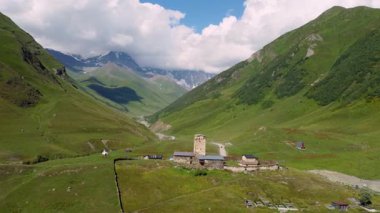 Lamaria Manastırı Kompleksi, tarihi Ushguli köyünde yeşil çayırlar arasında duruyor, Gürcistan Drone bölgesinin pitoresk Svaneti bölgesinde taş duvarları ve kulesi var..