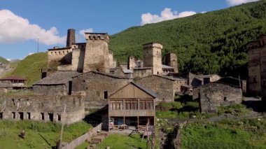 Görkemli taş kuleler ve geleneksel evler Ushguli, Svaneti, Gürcistan, UNESCO Dünya Mirası İnsansız Hava Aracı Bölgesi 'ndeki yemyeşil dağların karşısında duruyor..