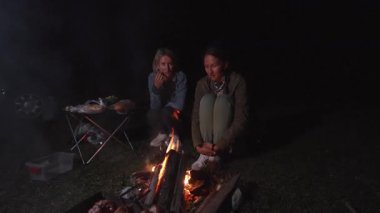 Dostlar ateş etrafında toplanır, ızgarada yemek yer, yıldızlı vahşi yaşamla dolu huzurlu bir gecenin tadını çıkarırlar, dostluğun sıcaklığı ve temiz havanın sükuneti içinde.