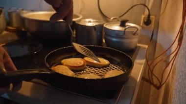 Dökme demir tavada krep pişirmek, dönüşüm sürecini gösteriyor. Fırının üzerindeki altın-kahverengi krepler Gürcistan mutfağının kırsal atmosferini oluşturur