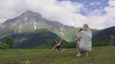 Kadın fotoğrafçı, Svaneti 'de Georgia' da parlak yaz güneşinin arka planına karşı renkli otlarla dolu pitoresk dağ çayırının arka planında meditasyon yapan esmer bir kadını yakaladı..