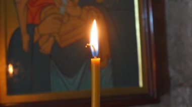 Sıcak mum ışığı, dinsel ikonun yanında usulca parlıyor, kutsal kilisenin içini huzur, meditasyon ruhuyla aydınlatıyor.