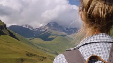 Sırt çantalı kadın dağ yolunda dikilip Shkhara Dağı 'nın uzak tepelerine bakan Svaneti' deki Ushguli Dağı 'na, Sahne Yolculuğu sırasında huzurlu anları kişiselleştiriyor.