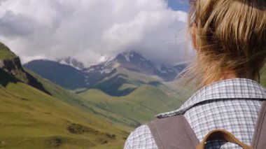 Sırt çantalı kadın dağ yolunda dikilip Shkhara Dağı 'nın uzak tepelerine bakan Svaneti' deki Ushguli Dağı 'na, Sahne Yolculuğu sırasında huzurlu anları kişiselleştiriyor.