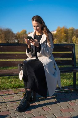 Genç bir kadın oturma odasında rahat bir kanepede dinlenirken komik bir yüz ifadesi takınıyor, neşeli ve kaygısız bir tavır sergiliyor. Dikey fotoğraf