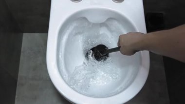 Profesyonel hademe, beyaz seramik klozeti iyice temizler. İnatçı kiri ve inatçı kiri ortadan kaldırmak için iç yüzeyleri siyah plastik fırçayla ovalar. yavaş çekim