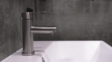 Çağdaş, paslanmaz çelik musluktan damlayan su damlacıkları, tesisat sorunları, su atıkları ve tamir ya da yenileme ihtiyacı