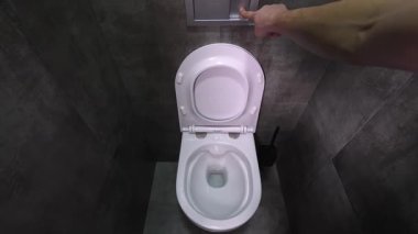 Pürüzsüz, beyaz seramik tuvaletin içine akan güçlü sifon suyu. Etrafı koyu gri fayanslı banyo döşemeleri ile çevrili. Modern ev temizliğini gösteriyor. ertelenmiş hareket