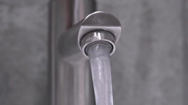 Profesyonel tesisatçı krom duş musluğunu manipüle ederek su basıncını ölçüyor. Ev bakımı sırasında modern gri kiremitli banyodaki akış dinamiklerini değerlendiriyor.