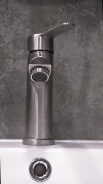 Çağdaş, paslanmaz çelik musluktan damlayan su damlacıkları, tesisat sorunları, su atıkları ve dikey video tamir veya yenileme ihtiyacı