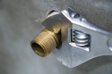 Tesisatçıya yakın plan pirinç boru montajı ayarlanabilir ingiliz anahtarı kullanarak, tesisat bakımı ve onarımı konusunda uzmanlık ve hassasiyet gösteriyor.