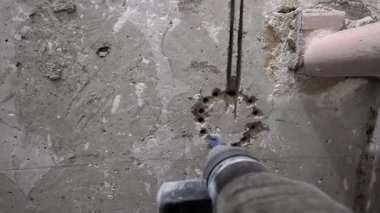 İnşaat işçisi beton zeminde bir dizi delik açmak için döner çekiç kullanıyor, boru tesisatı veya diğer inşaat işleri için hazırlanıyor