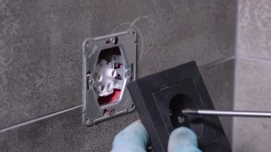 Eldivenli eller dikkatle konum ve yeni siyah güç kapağı güvenli tornavida kullanarak, modern gri karo üzerinde elektrik kurulumu tamamlanan