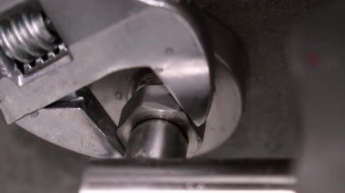 Tesisat ve musluğun bakımında metal boru somununu sıkılaştırmak için ayarlanabilir anahtar kullanan yetenekli bir teknisyen..