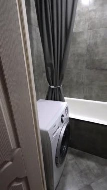 Gri modern banyo yenilemesi çamaşır makinesi kurulumu, duş ve lavabo kurulumu gösterimi ve perde ve havlu yerleştirme dahil son rötuşlar. dikey video.