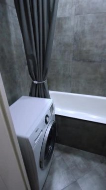 Gri modern banyo yenilemesi çamaşır makinesi kurulumu, duş ve lavabo kurulumu gösterimi ve perde ve havlu yerleştirme dahil son rötuşlar. dikey video.