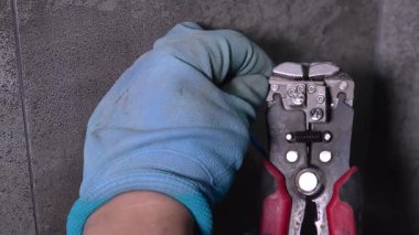 Koruyucu eldiven giyen elektrikçi tel sökücüleri kullanarak yalıtımı dikkatlice söker ve bağlantı kutusunun içindeki bağlantıya hazırlar.