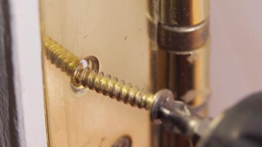 Prezervatif takan profesyonel inşaat işçisi, hassas montaj sırasında metal bağlayıcıyı el değmemiş beyaz iç duvara sıkmak için elektrikli tornavida takıyor.