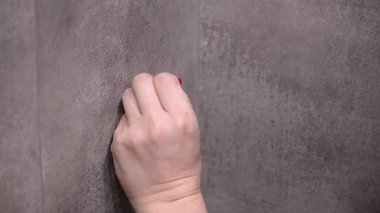 Profesyonel inşaat işçisi, ev yenileme projesi sırasında çekiç kullanılarak hassas onarımlar için yüzeyi hazırlayan, gri kartonlu duvara kırmızı plastik tıpa takıyor.