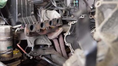 Araba motorundan egzoz manifoldu, profesyonel garaj ortamında detaylı araba tamir işlemi sırasında karmaşık iç bileşenleri açığa çıkarıyor