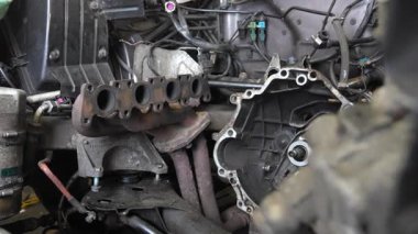 Araba motorundan egzoz manifoldu, profesyonel garaj ortamında detaylı araba tamir işlemi sırasında karmaşık iç bileşenleri açığa çıkarıyor