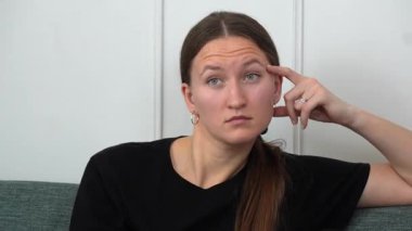 Genç bir kadın rahat bir koltukta oturup televizyon izliyor uzaktan kumanda kullanıyor, kanal değiştiriyor, düşünüyor ve çeşitli yüz ifadeleri yapıyor.
