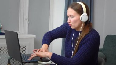 Kulaklık takmak, dizüstü bilgisayarla çalışmak, ev işyerinde derin bir konsantrasyon ve verimlilik sergilemek, modern dijital yaşam tarzını somutlaştırmak.