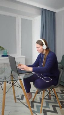 Kulaklık takmak, dizüstü bilgisayarla çalışmak, ev işyerinde derin bir konsantrasyon ve verimlilik sergilemek, modern dijital yaşam tarzını somutlaştırmak.