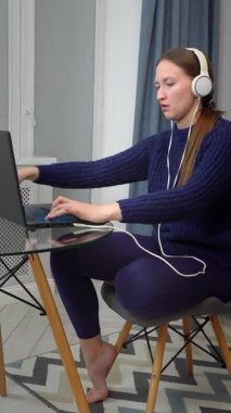 Kulaklık takmak, dizüstü bilgisayarla çalışmak, ev işyerinde derin bir konsantrasyon ve verimlilik sergilemek, modern dijital yaşam tarzını somutlaştırmak.