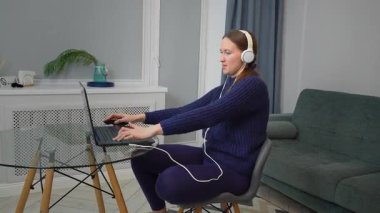 Kulaklık takmak, dizüstü bilgisayarla çalışmak, ev işyerinde derin bir konsantrasyon ve verimlilik sergilemek, modern dijital yaşam tarzını somutlaştırmak.