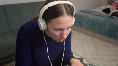 Çevrimiçi oyun oynayan, kulaklık takan, sanal dünyada gezinen, dağınık yatak odası ortamında laptop ve fare kullanan genç bir kadın.