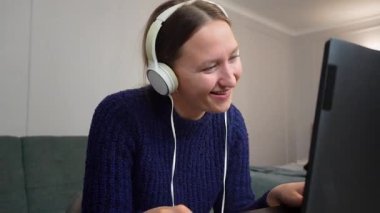 Çevrimiçi oyun oynayan, kulaklık takan, sanal dünyada gezinen, dağınık yatak odası ortamında laptop ve fare kullanan genç bir kadın.