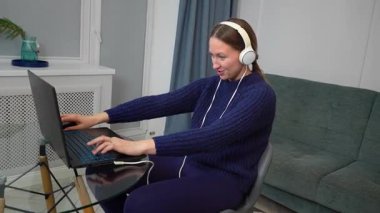 Çevrimiçi oyun oynayan, kulaklık takan, sanal dünyada gezinen, dağınık yatak odası ortamında laptop ve fare kullanan genç bir kadın.