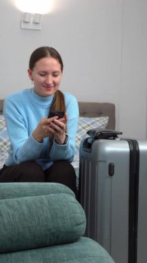 Akıllı telefon planları yapan bir kadın uçak bileti, otel, ulaşım, iş seyahatine hazırlanmak, rotaları kontrol etmek, mobil uygulama dikey video kullanarak taksi çağırmak gibi seyahatler yapar.